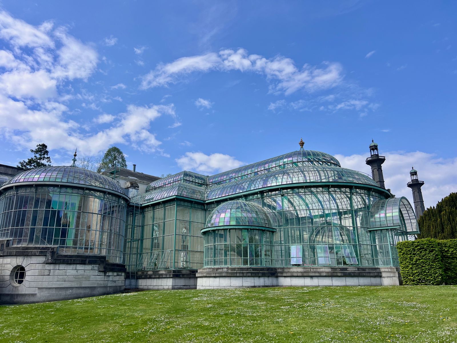 Beautiful historic greenhouse with glass domes and towers under a vibrant blue sky in Brussels, Belgium