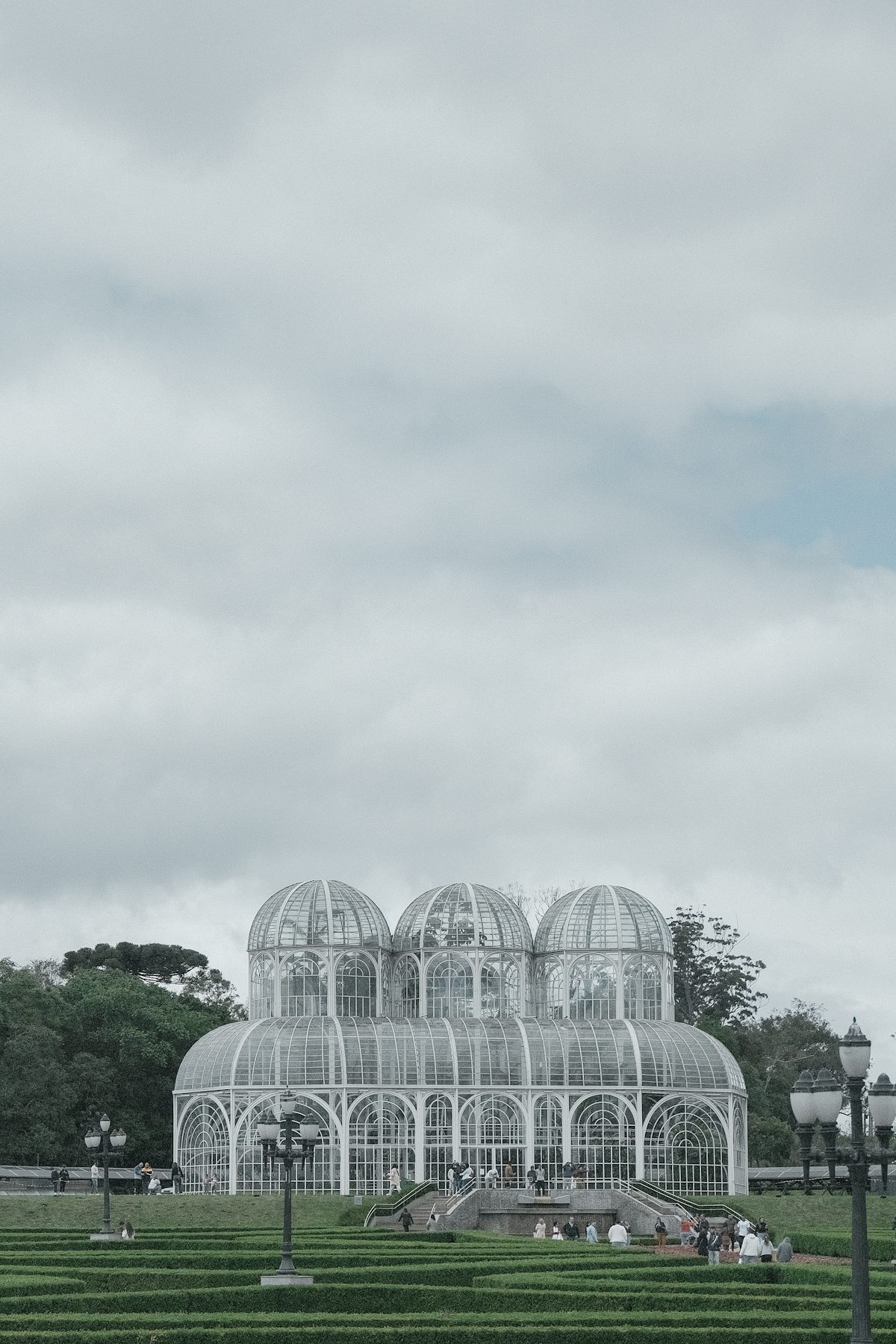 Glass-paneled geodesic dome conservatory structures in a botanical garden under overcast sky